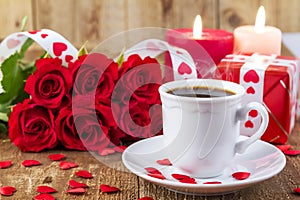 Cup with coffee in front of bouquet of red roses